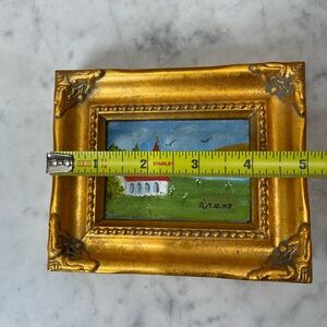 framed miniature painting of landscape with a small church